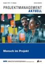 „PROJEKTMANAGEMENT AKTUELL“, „Mensch im Projekt“. Zwei Personen betrachten Notizen auf einer Glaswand.