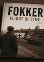 "FOKKER FLIGHT OF TIME NOVEL". Ein Mann blickt auf ein historisches Gebäude mit Flugzeugteilen und einem Auto.