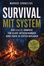 „Survival mit System“ in großer Schrift. Lagerfeuer, Rucksack, Kompass. Dunkler Wald im Hintergrund.