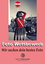 "Foto Wettbewerb. Wir suchen dein bestes Foto." Eine Person in Tracht fotografiert ein bearbeitetes Verkehrsschild.