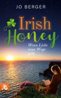 „Jo Berger. Irish Honey. Wenn Liebe neue Wege geht.“ Frau liest beim Sonnenuntergang an einer Klippe.