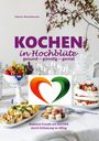„KOCHEN in Hochblüte: gesund – günstig – genial“. Bunter Tisch mit Obst, Kuchen und Blütenzweig, zentrales Herz-Logo.