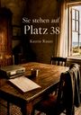 „Sie stehen auf Platz 38. Katrin Rauer.“ Ein rustikaler Raum mit Holztisch, Stuhl, Ordner, Tasse, Fensterblick auf Strand.