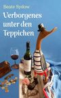 „Beate Sydow. Verborgenes unter den Teppichen.“ Ein Holzvogel mit Hut, Weinflasche, Glas, Rose, Münzen und Muscheln.