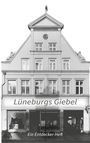 „Lüneburgs Giebel“ und „Ein Entdecker-Heft“ sind die Texte auf einer Hausfassade im traditionellen Architekturstil.