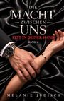 „Die Macht zwischen uns: Fest in deiner Hand, Band 1, Melanie Judisch“. Männliche Hand hält Handgelenk auf schwarzem Stoff.
