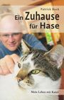 "Ein Zuhause für Hase" von Patrick Buck. Vordergrund: Eine Katze entspannt, im Hintergrund ein Mann mit Brille.