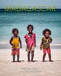 MADAGASCAR IMPRESSIONEN II. Drei fröhliche Kinder am Strand vor dem Meer, barfuß in bunter Kleidung.
