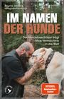 Text: IM NAMEN DER HUNDE. Ein tätowierter Mann berührt liebevoll die Stirn eines großen Hundes im Wald.