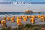 „globetrotter OSTSEE 2027 Von behaglichen Strandkörben und rauen Küsten.“ Strandkörbe am Sandstrand vor einem Steg im Meer.