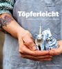 „Töpferleicht: Tonarbeiten mit Hand und von Herzen.” Person in Schürze hält drei getöpferte Katzenfiguren.