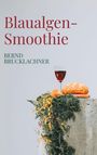 "Blaulagen-Smoothie" und darunter "Bernd Brucklachner". Ein Glas Rotwein, Brot und Blumen auf einem Betonsockel.