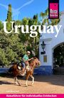 "Uruguay", "Reiseführer für individuelles Entdecken". Ein Mann reitet auf einem Pferd vor einem weißen Stadttor.