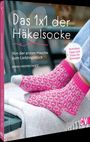 „Das 1x1 der Häkelsocke“. Darunter pink-graue gehäkelte Socken auf einem Tuch, Jeans im Hintergrund.