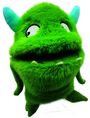 Grünes, flauschiges Monster mit zwei blauen Hörnern und großen Augen. Es hat einen aufgerissenen Mund mit kleinen Zähnen.