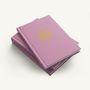 Pinkes Buch mit der Aufschrift "2027", einem goldenen Muster und Text "Flower of Life." Aufeinandergestapelt.