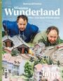 Der Text "Miniatur Wunderland - Alles, was man wissen muss" erscheint über zwei Personen, die sich über eine Modelleisenbahn beugen.