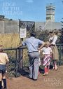 Texte: "EDGE OF THE VILLAGE", "GRENZLAND". Eine Familie beobachtet eine Grenzanlage mit Turm. Frau mit Fernglas.