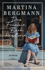 „Martina Bergmann: Das Fräulein Buchhändlerin, Roman, EISELE“. Illustration: Frau in blauem Kleid mit Buch vor Buchhandlung.