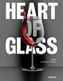"HEART OF GLASS" in großen weißen Buchstaben. Ein Weinglas mit roter Flüssigkeit in dynamischer Bewegung.