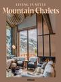 "LIVING IN STYLE Mountain Chalets" in Beige, zeigt ein stilvolles Chalet-Interieur mit Kamin, Fellmöbeln und Bergblick.