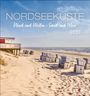 Nordseeküste: Wind und Wellen - Sand und Meer 2027. Strand mit Strandkörben, ein rotes Strandhaus links, Meer im Hintergrund.