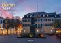 „Bonn 2027“ und „Postamt“ sind zu lesen. Im Vordergrund steht eine Statue auf einem Platz vor einem beleuchteten Gebäude.