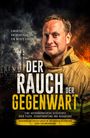 Der Titel lautet "Der Rauch der Vergangenheit". Ein Feuerwehrmann und eine Frau im Sari stehen vor einem Sonnenuntergang.