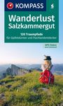 Logo "KOMPASS". Text: "Wanderlust Salzkammergut. 120 Traumpfade für Gipfelstürmer und Flachlandentdecker. GPS-Daten zum Download." Frau mit rotem Rucksack sitzt auf Wiese mit Bergblick.