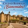 Text: "Ciudad Rodrigo, ¡Bienvenidos! A Historic City. A Warm Welcome. A New Friendship." Steinmauern, Laterne, blauer Himmel.