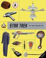 "STAR TREK IN 100 OBJECTS" steht in der Mitte. Verschiedene ikonische Star-Trek-Gegenstände sind um den Text herum gruppiert.