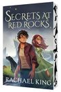 „SECRETS AT RED ROCKS“ und „RACHAEL KING“. Zwei Figuren blicken aufmerksam, eine Robbe im Vordergrund.