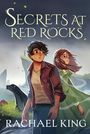 „Secrets at Red Rocks“ von Rachael King; zwei Jugendliche blicken nachdenklich, rechts weht ein Trenchcoat im Wind.