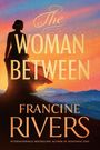 "The Woman Between" und "Francine Rivers" in großen Buchstaben; eine Frau steht vor einem bunten Himmel und Berglandschaft.