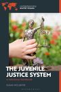 "THE JUVENILE JUSTICE SYSTEM", eine Statue der Justitia, gehalten von einer Hand, vor einem unscharfen, blühenden Hintergrund.