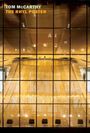 Oben links stehen die Worte "Tom McCarthy The Rhyl Poster" in gelb und weiß. Großes Fenster zeigt hell erleuchtetes Gebäudeinnere.