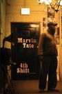 Texte: "Marvin Tate," "4th Shift," "EXIT." Unscharfer Mann in dunklem Raum, im Hintergrund Fotos und Neonlicht.